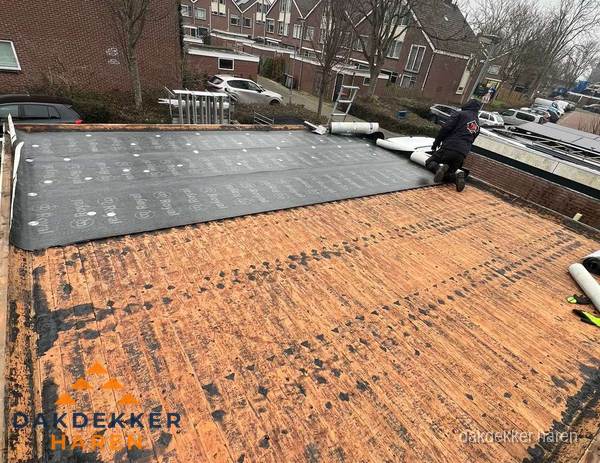 Dakdekker legt onderlaag op plat dak met houten constructie in Haren