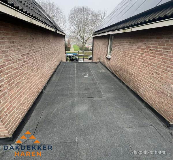 Plat dak met bitumen dakbedekking tussen bakstenen muren in Haren Plat dak met bitumen dakbedekking tussen bakstenen muren in Haren