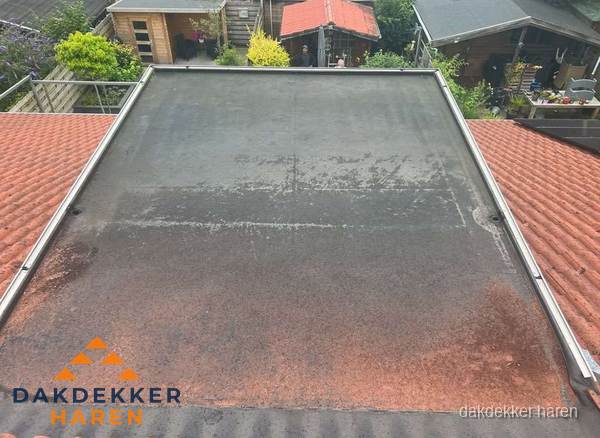 Verouderd plat dak met slijtage tussen schuine daken in Haren Verouderd plat dak met slijtage tussen schuine daken in Haren