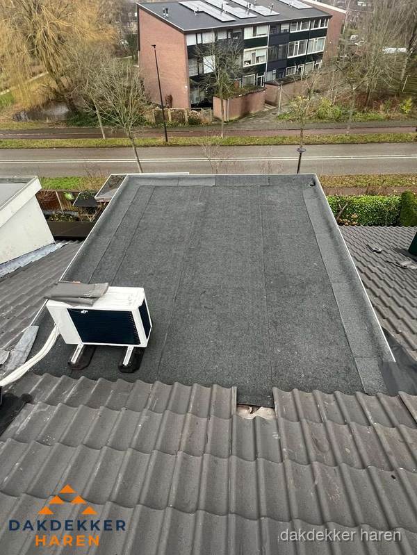 Plat dak inspectie met bitumen bedekking naast schuin pannendak in Haren